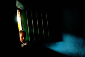 Color photograph 'Peeking through a window' (2008) by Au00efda Muluneh, looking into a room filled with various domestic objects.