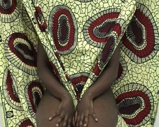 Artwork 'Still Life with Textiles' (2005u20132007) by Grace Ndiritu, showing a person sitting surrounded by highly patterned fabrics.