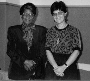Brenda Cooper and Phyllis Ntantala sitting next to each other with folded hands at a University of Cape Town celebration.